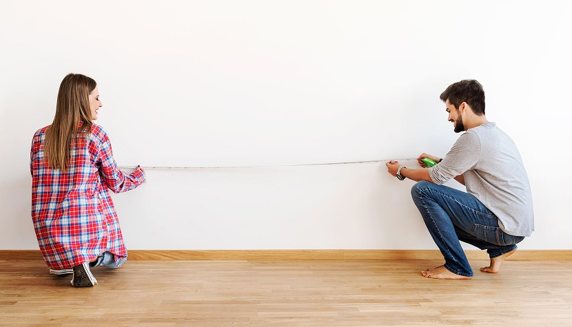 Молодая пара измеряет площадь квартиры Как самостоятельно рассчитать жилую площадь квартиры? Молодая пара производит замеры площади